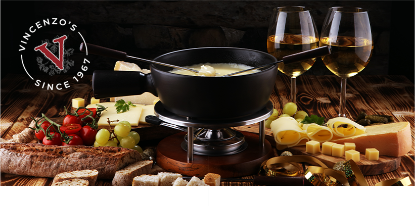 Fondue on a table with cheese, bread and wine